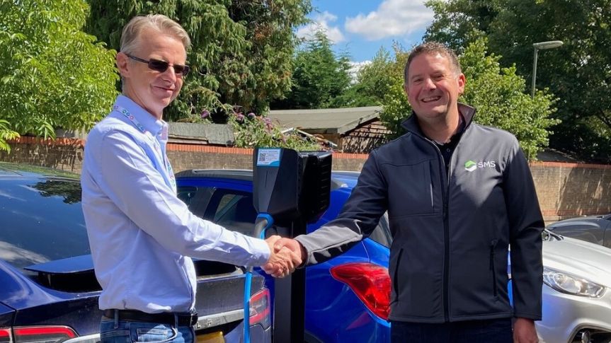 two men shake hands outside a public charge point
