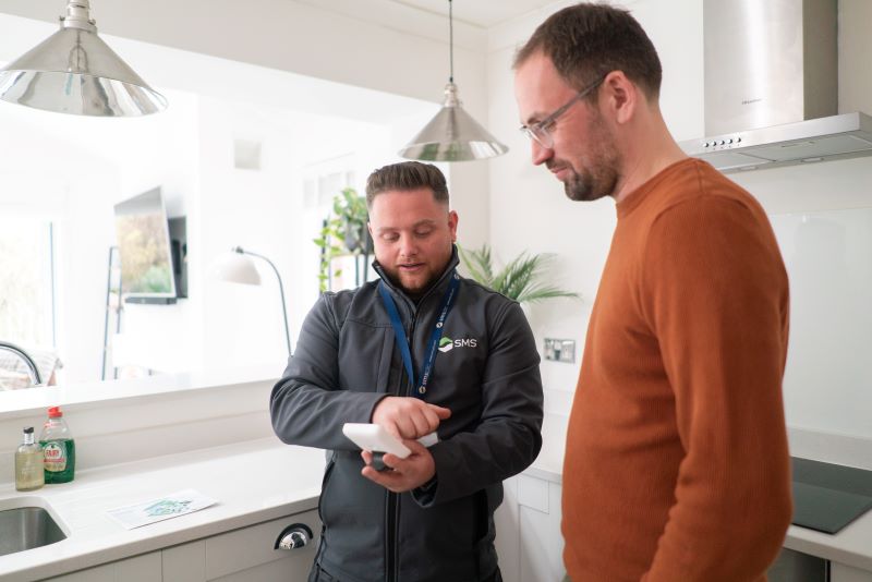 A smart meter installer shows a customer their energy usage on an In-Home DiSplay (IHD)
