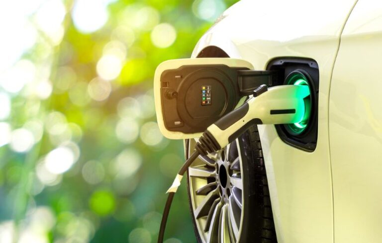 An electric vehicle bathed in sunlight being powered with electricity by an EV charger