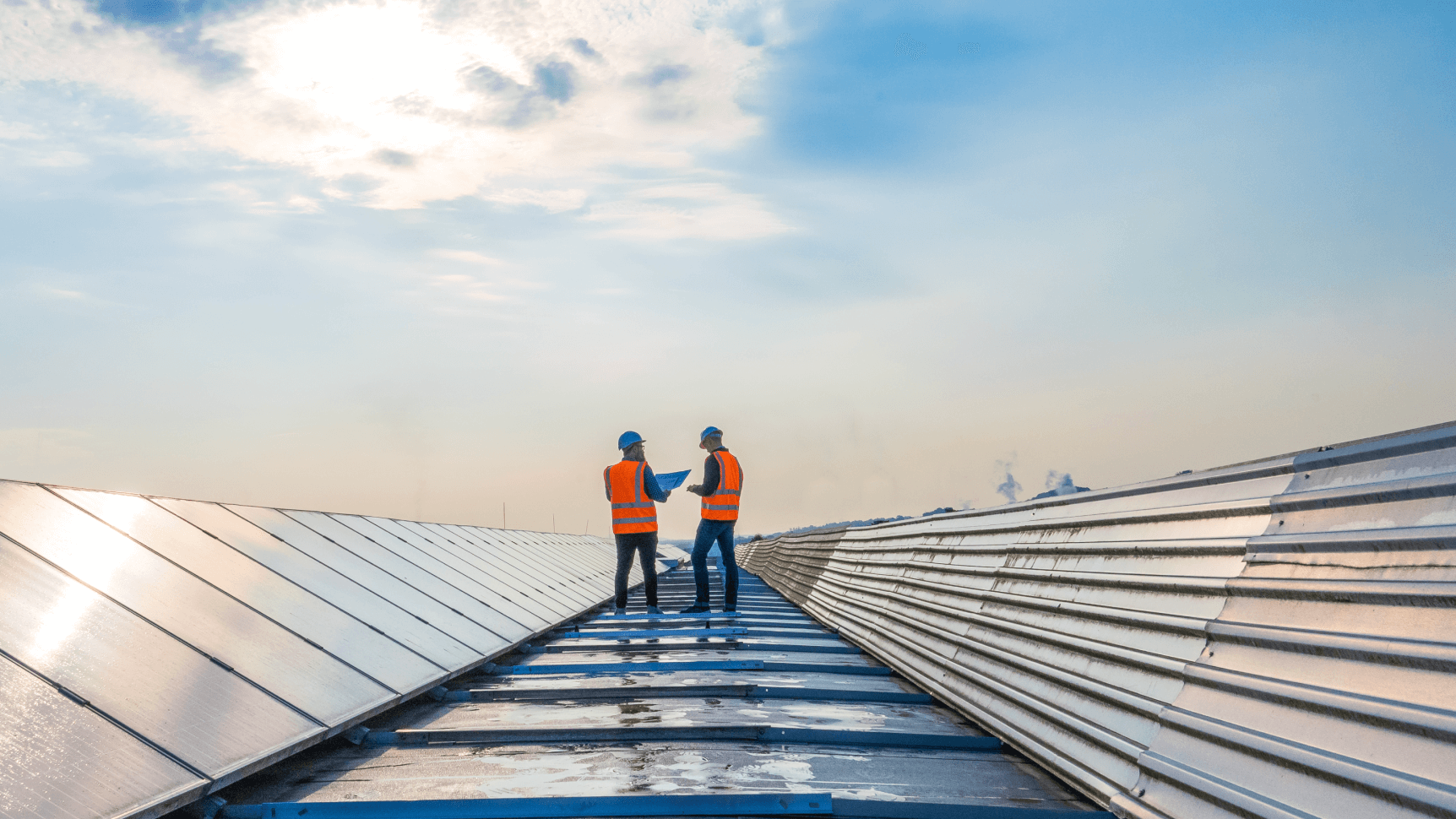 construction workers looking at plans next to solar panels